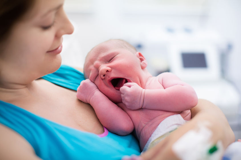 A mother holds a newborn to her chest.