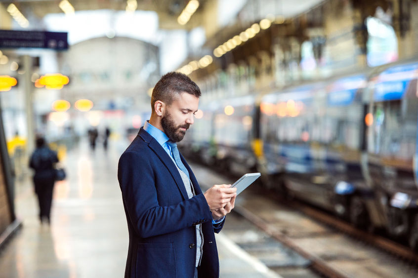 A man checks his smartphone on a subway platform.