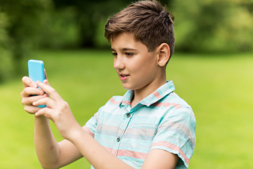 A young boy holds a smartphone while completing a virtual scavenger hunt.