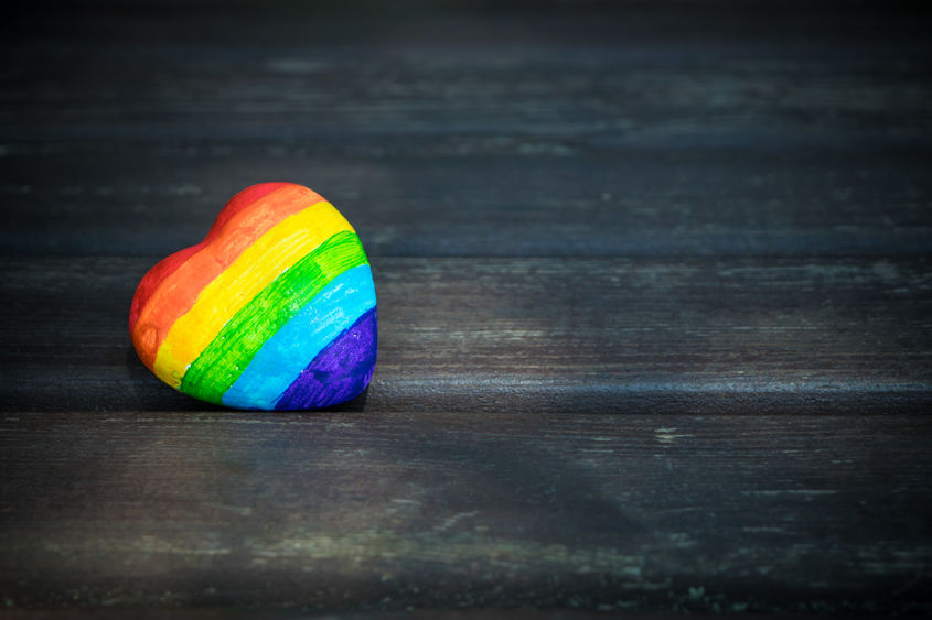 A heart-shaped rock painted with the colors of the rainbow.