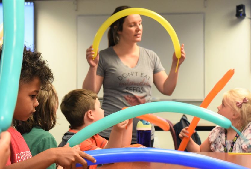 A female instructor bends a long balloon during a youth summer class about the Macy's Thanksgiving Day parade.