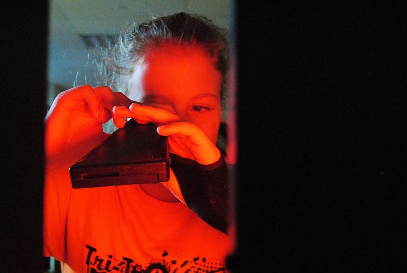 A girl looks through a light spectrum during a science experiment.