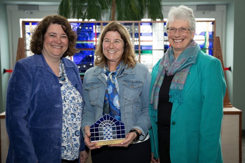 Women's Engagement Council board members Melanie Ford and Priscilla Hamilton present the Mary Behrend Impact Award to Paula J. Dombrowski.
