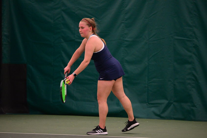 A Penn State Behrend tennis player prepares to serve.