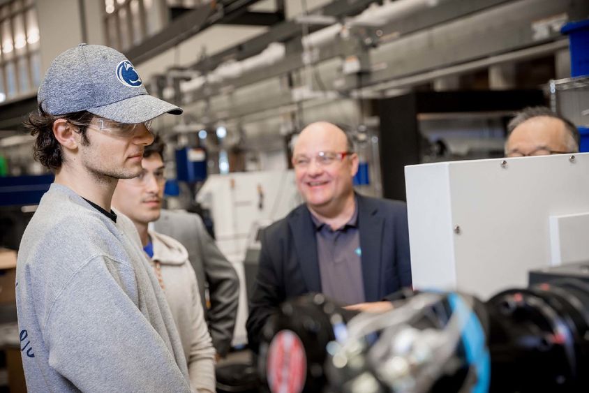 Two students stand at an injection-molding machine at Penn State Behrend.