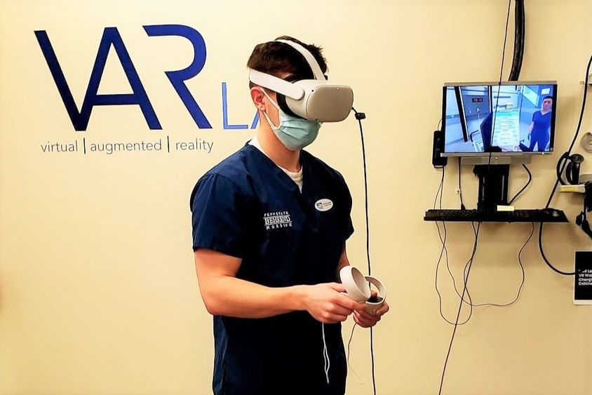 A male student in the nursing program at Penn State Behrend wears an Oculus headset while completing a VR simulation.