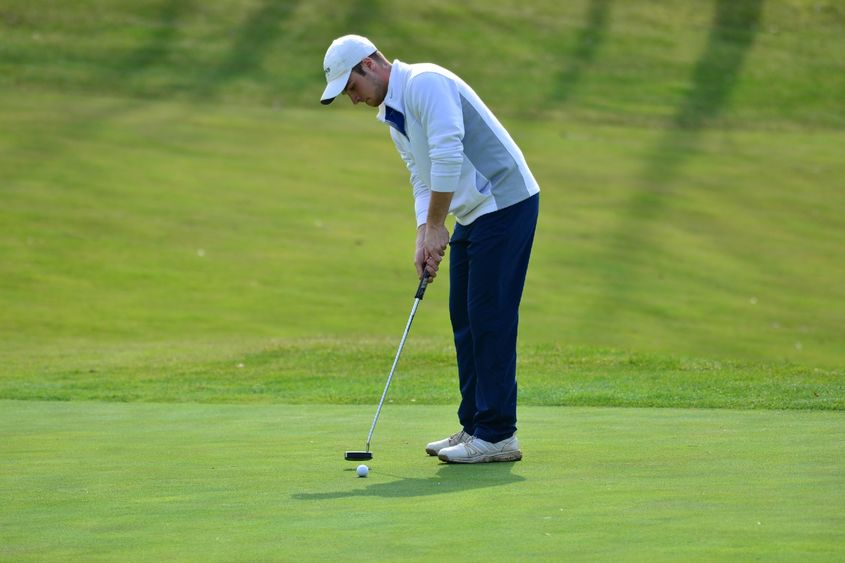 A Penn State Behrend golfer putts the ball.