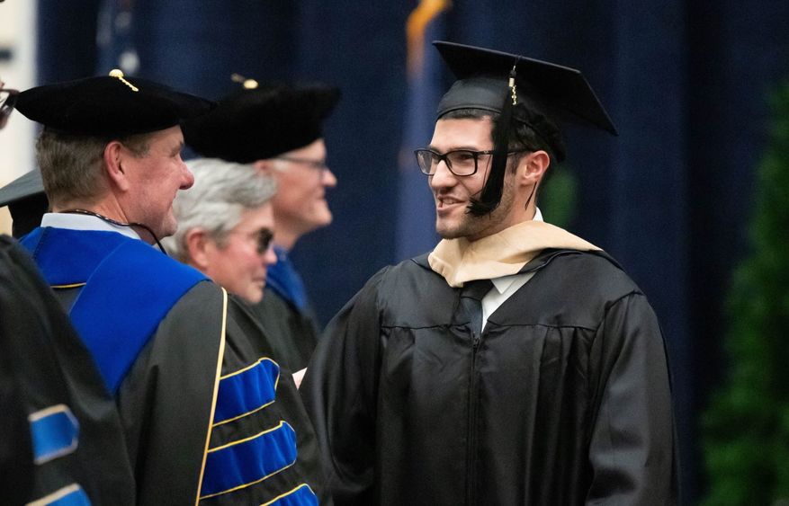 A graduate smiles at a faculty member during Penn State Behrend's commencement program.