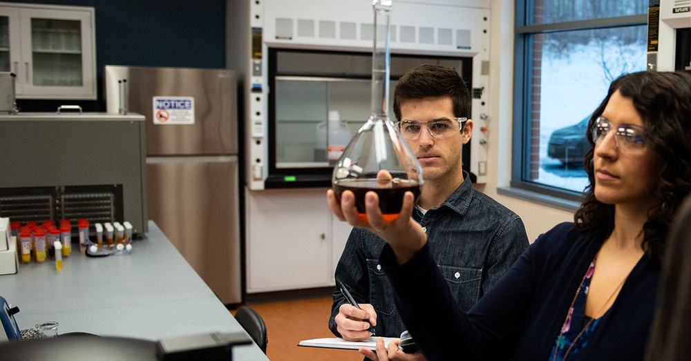 Two researchers examine a liquid in a beaker while working in a chemistry lab at Penn State Behrend.