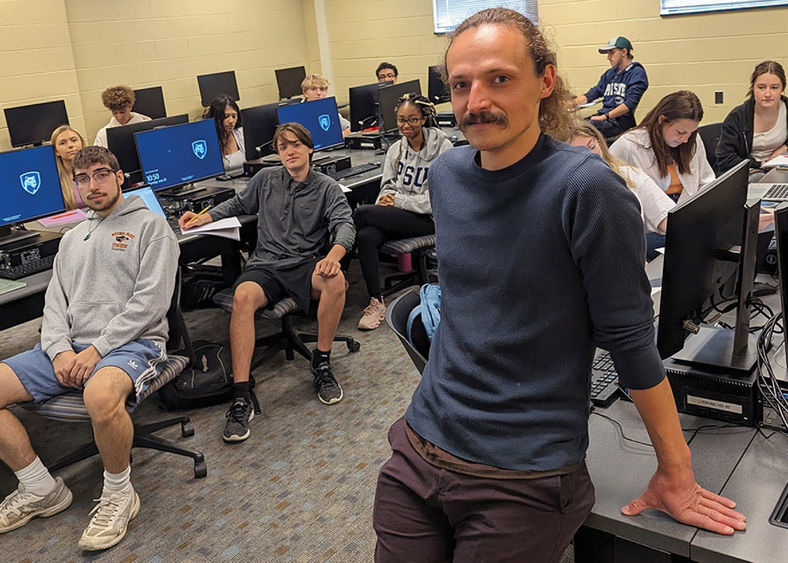 Penn State Behrend faculty member Jasper Sachsenmeier poses in a classroom with several students.