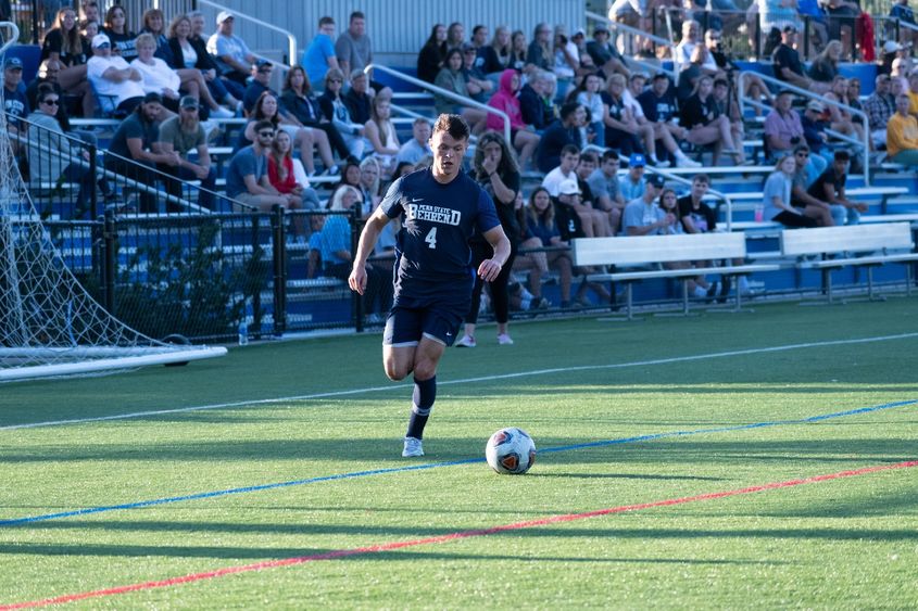 A Penn State Behrend soccer player dribbles the ball upfield.