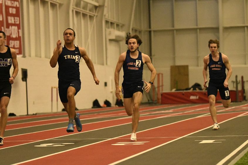 Penn State Behrend runners race around an indoor track.