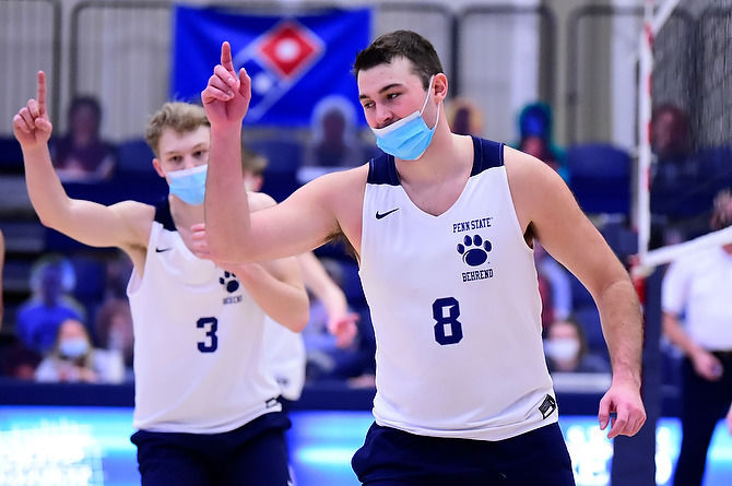Two members of the Penn State Behrend men's volleyball team celebrate after winning a point.