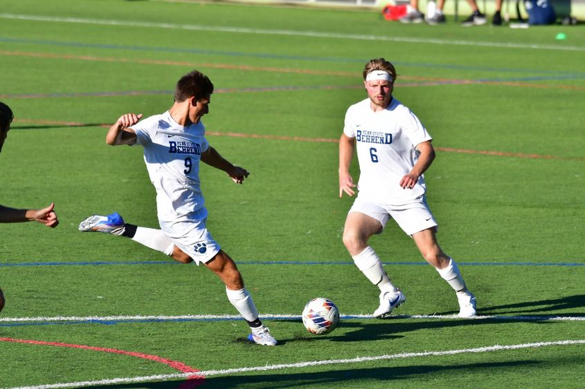 Two members of Penn State Behrend's men's soccer team advance toward the goal.
