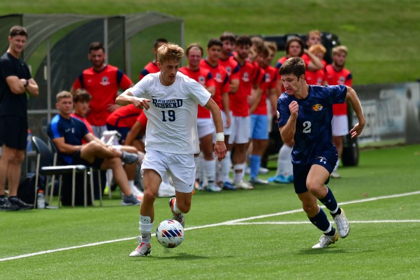 A Penn State Behrend soccer player dribbles the ball past an opponent.