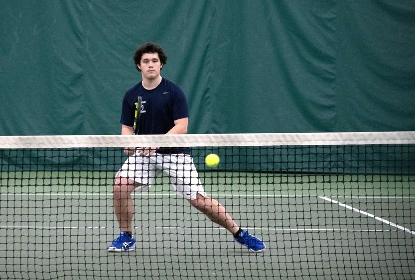 A member of the Penn State Behrend men's tennis team prepares to hit a ball.