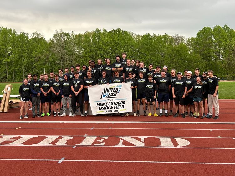 The Penn State Behrend men's track and field team celebrates with the United East championship banner.