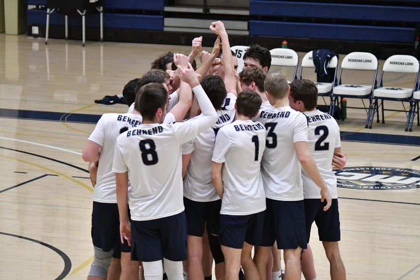 Members of the Penn State Behrend men's volleyball team celebrate in a huddle after winning a point.