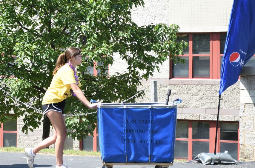 A female student pushes a luggage cart during Penn State Behrend's move-in day.