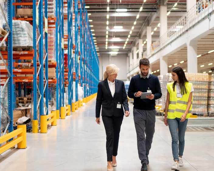 Three people walk in a warehouse.