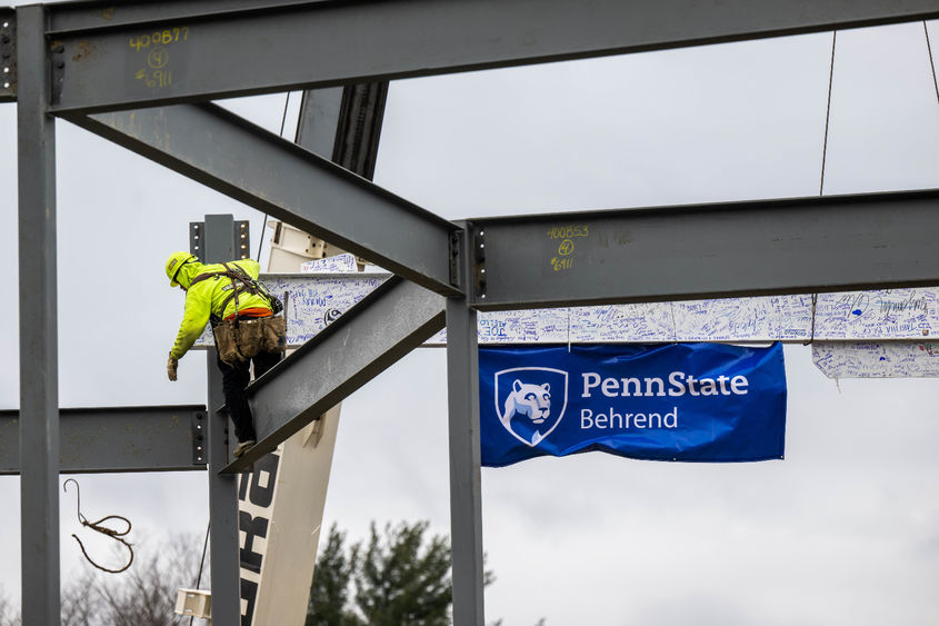 A steelworker helps set a 32-foot beam while building Penn State Behrend's new Erie Hall.