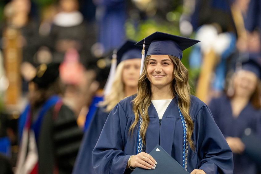 A Penn State Behrend graduate smiles after receiving her degree.