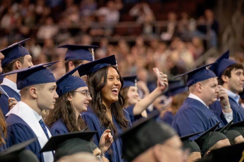 Students smile and point during Penn State Behrend's spring commencement program.