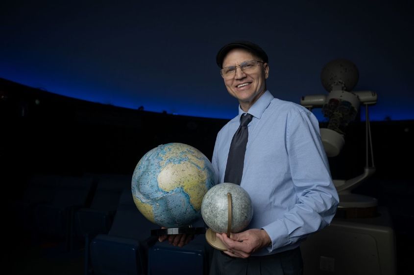 Darren Williams, an astronomer at Penn State Behrend, holds models of the Earth and the moon.