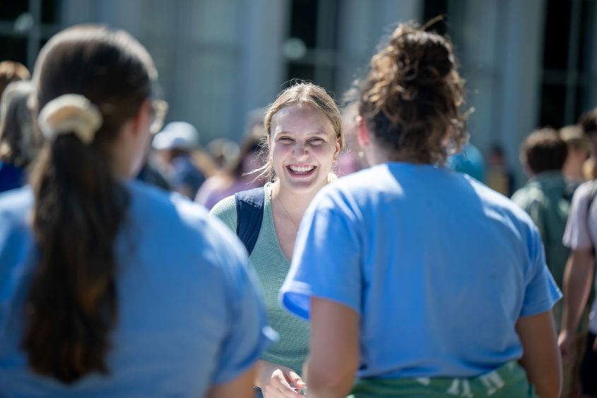 A female student smiles while talking to two others at Penn State Behrend's Discovery Fair.