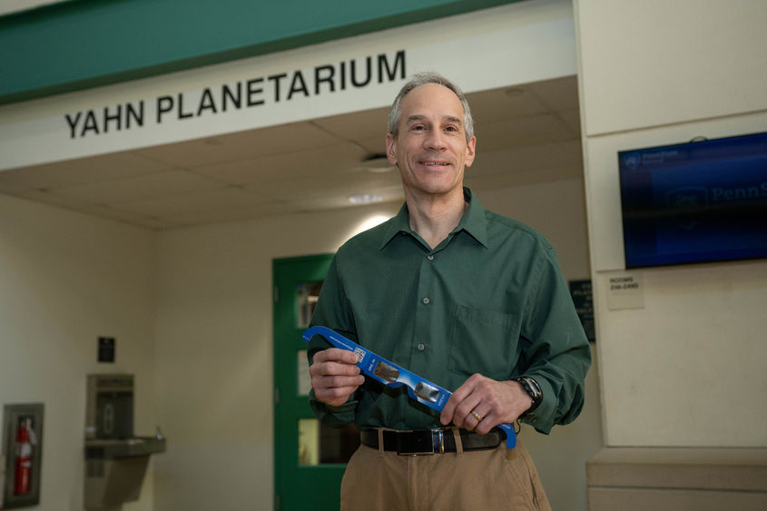 Jim Gavio, director of Penn State Behrend's Yahn Planetarium, holds eclipse glasses.