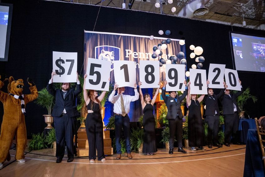 A row of Penn State Behrend students hold up placards with numbers that show the fundraising total in the college's six-year campaign.