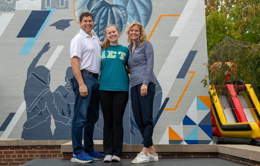 A student poses with her parents at Penn State Behrend's Parents, Families and Alumni Weekend.