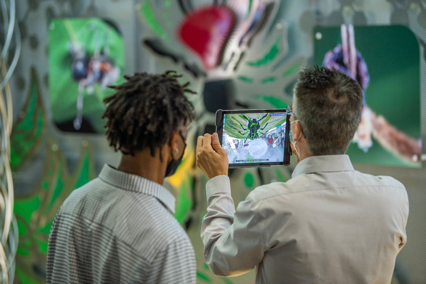 Two men use an iPad to explore the augmented reality element of an interactive art exhibit.
