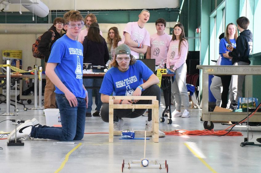 Two students watch as a model car is pushed down a test zone at Penn State Behrend's Science Olympiad.