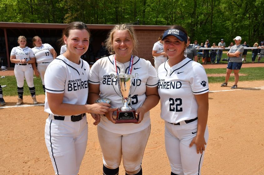 Three Penn State Behrend softball players hold the AMCC runner-up trophy.