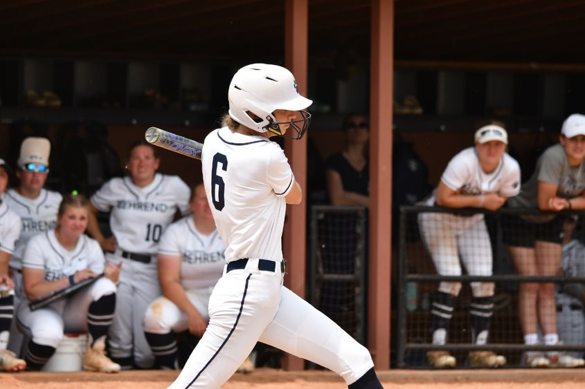 A Penn State Behrend softball player swings at a pitch.