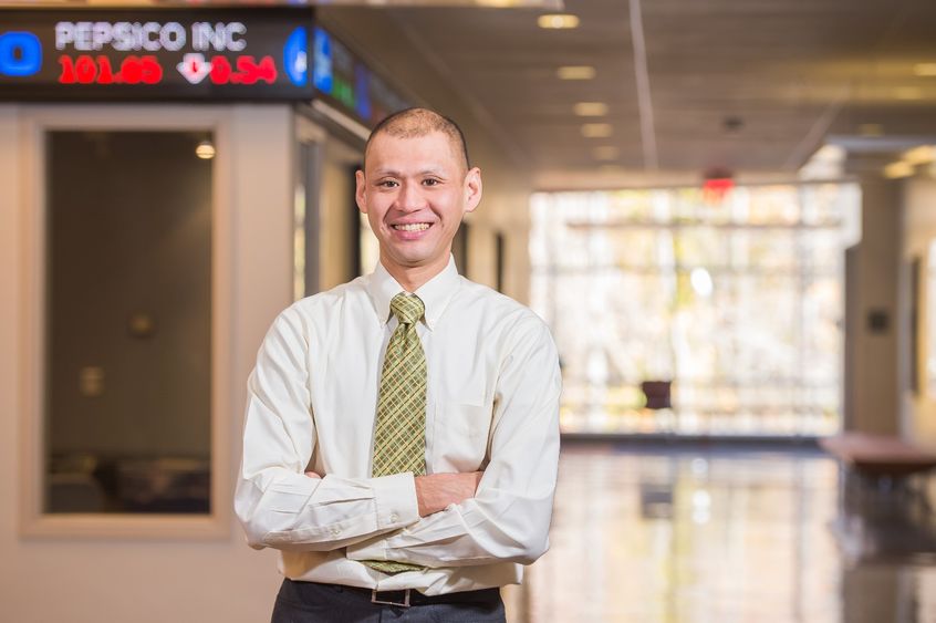 A Penn State Behrend faculty member stands outside the financial trading lab in Burke Center.