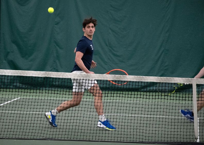 A Penn State Behrend tennis player watches a backhand shot cross the net.