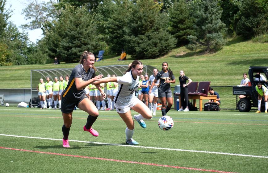 A Penn State Behrend women's soccer player runs past a defender.