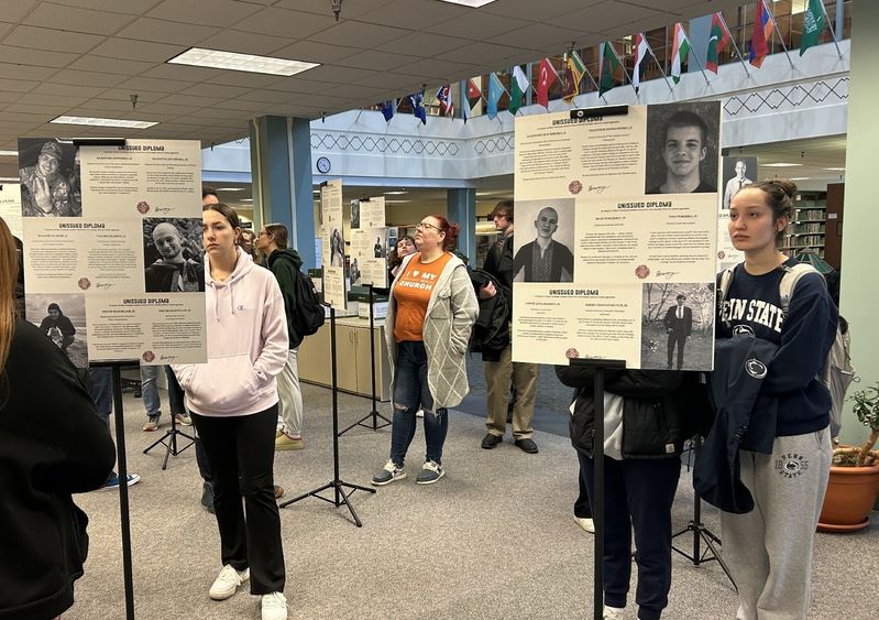 Students look at posterboards with information about victims of the war in Ukraine.