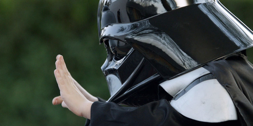 A boy in a Darth Vader mask tries to use magic to move a car.