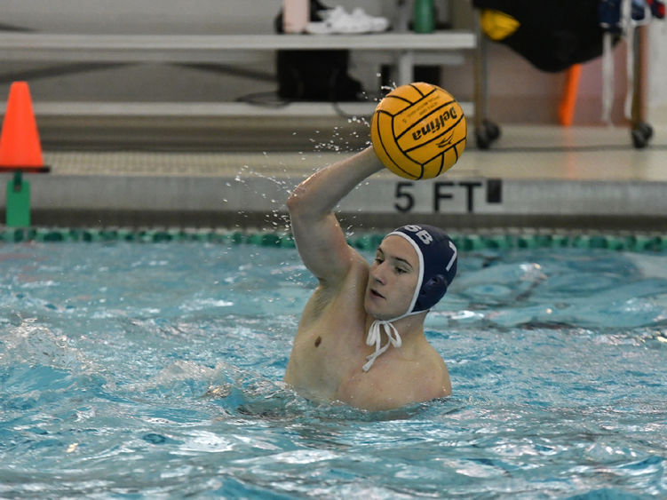 A Penn State Behrend men's water polo player catches the ball.