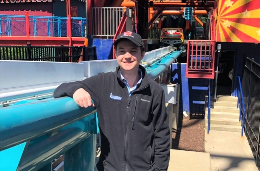 Penn State Behrend graduate William Friedlander stands next to a roller coaster track.