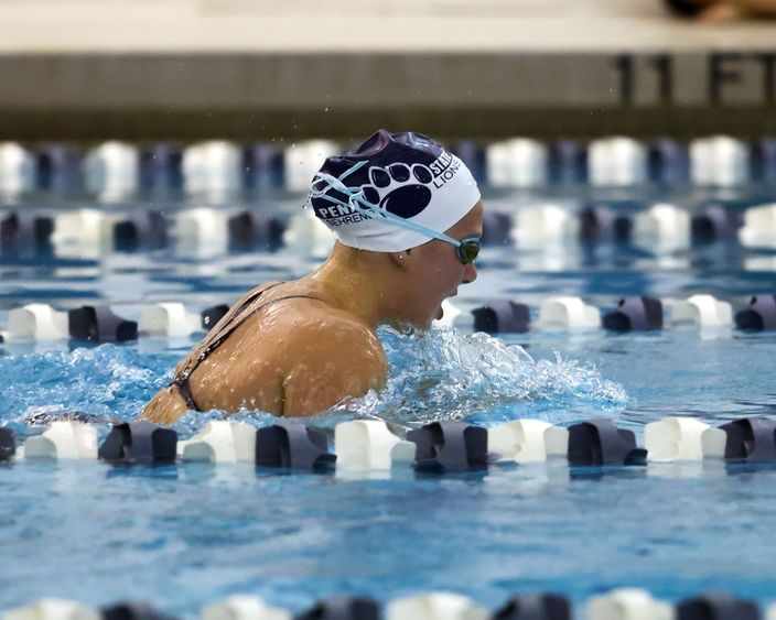 A female Penn State Behrend swimmer competes in a breaststroke race.
