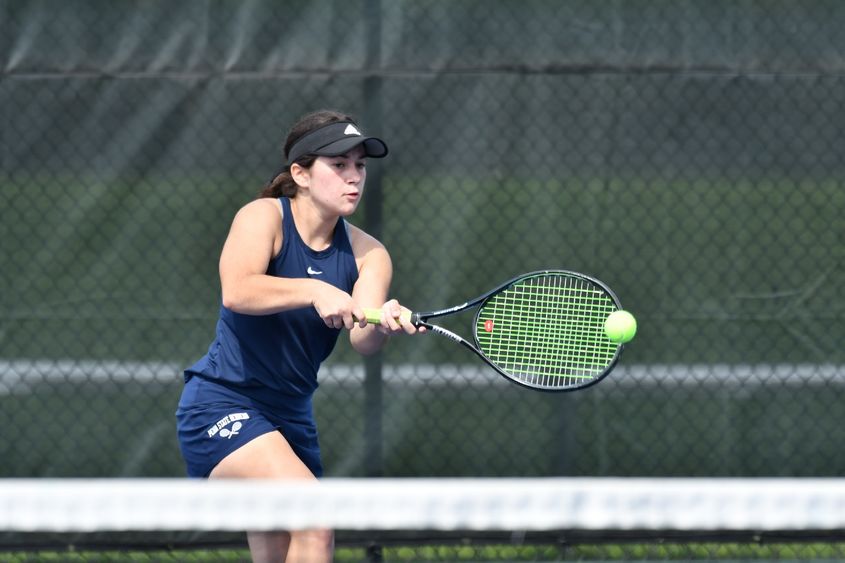 A Penn State Behrend tennis player hits a backhand.