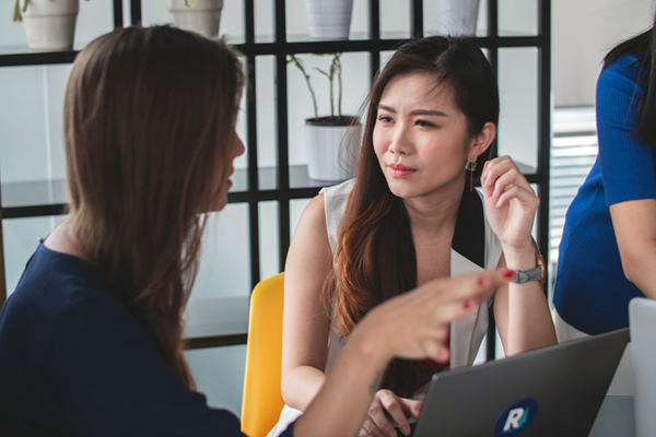 Two female students talking in front of a laptop computer