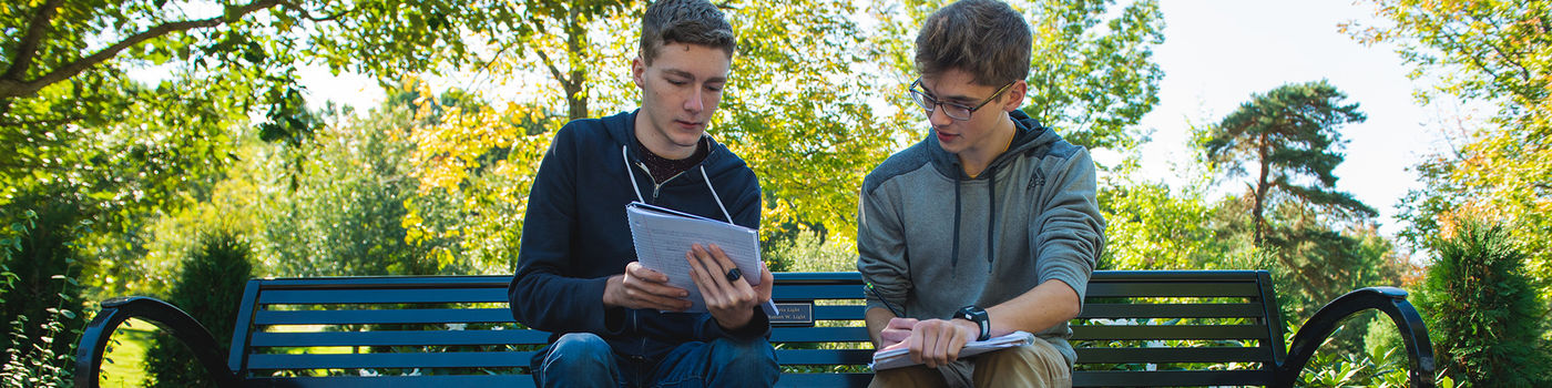 Two male students studying on a bench on the Penn State Behrend campus.