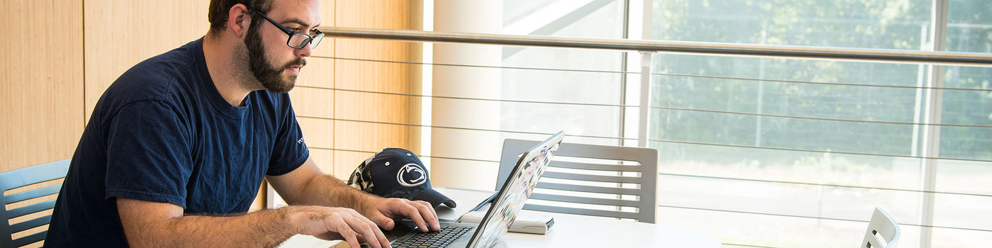 A Penn State Behrend working on a laptop computer