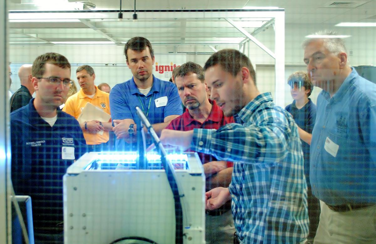 People look at a 3D printer in Penn State Behrend's Innovation Commons.