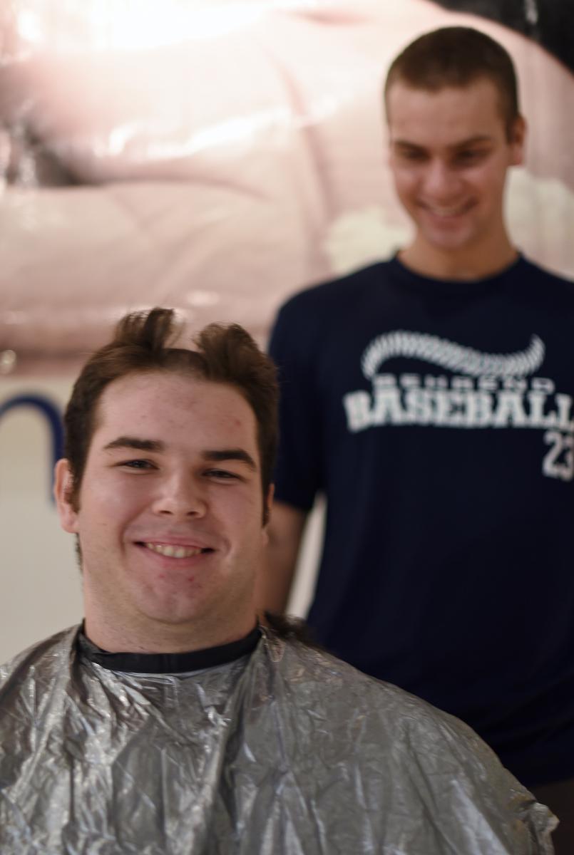 A Penn State Behrend baseball player has his hair cut.